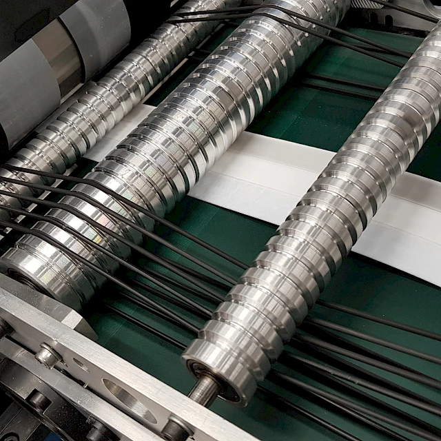 Cut white cards under spiral rollers on conveyor