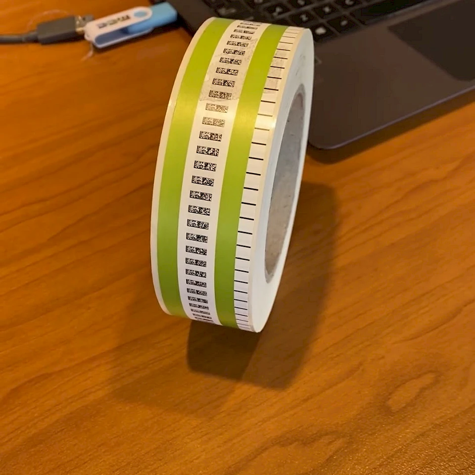 Green barcode printed roll beside laptop