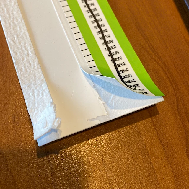 Green scale strip peeled from white pad on desk