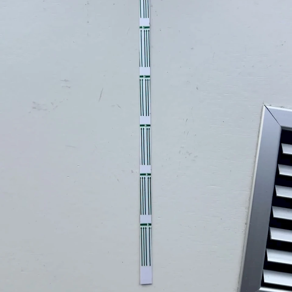Green striped test strip on white wall
