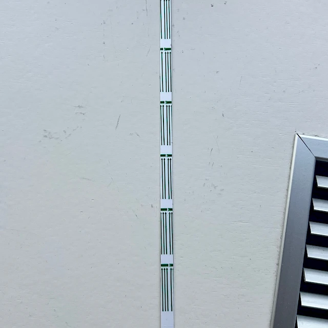 Green striped test strip on white wall