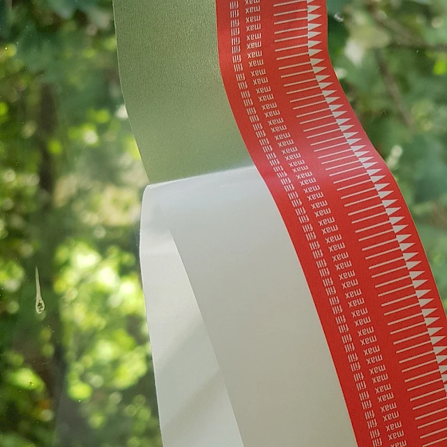 Red printed cover tape strip against trees