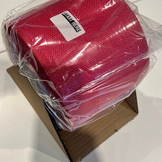 Red textured material roll in plastic bag