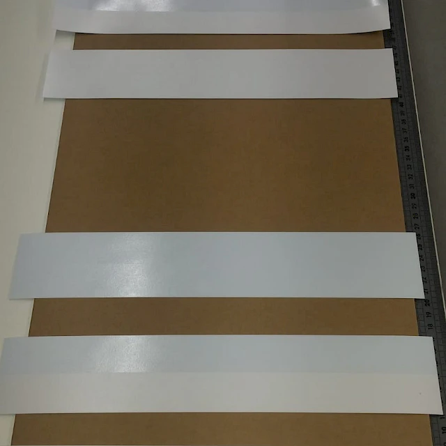 White card strips laid on cardboard bench