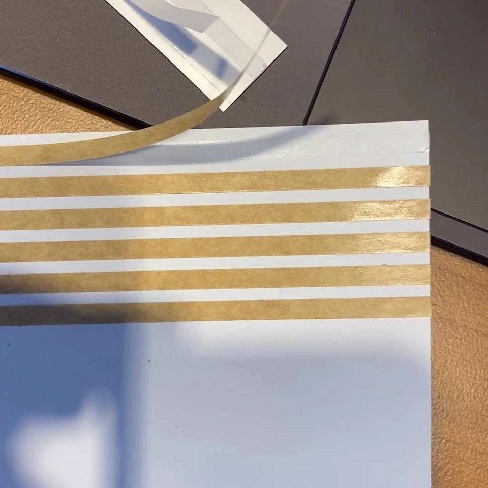 White card with brown adhesive stripes peeling