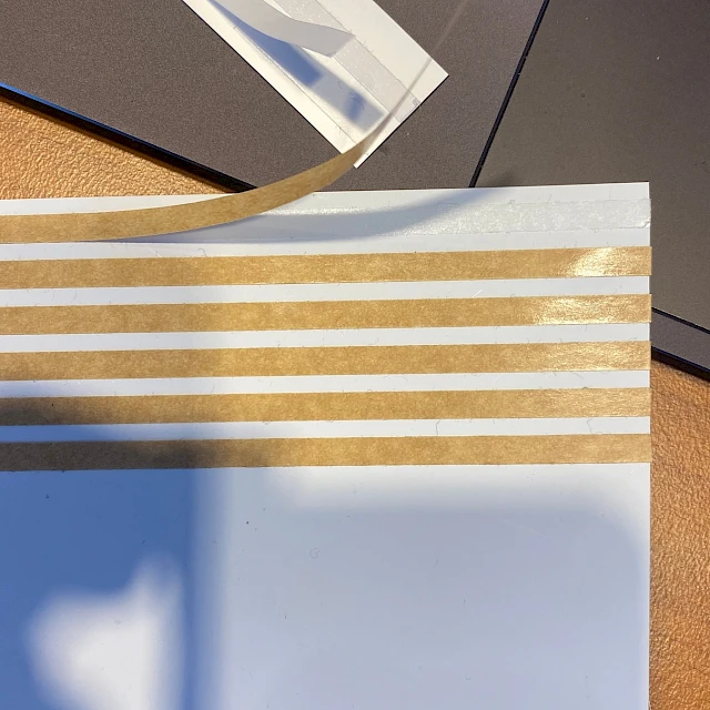 White card with brown adhesive stripes peeling