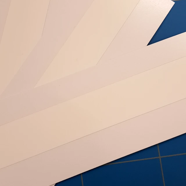 White laminated cards fanned on cutting mat