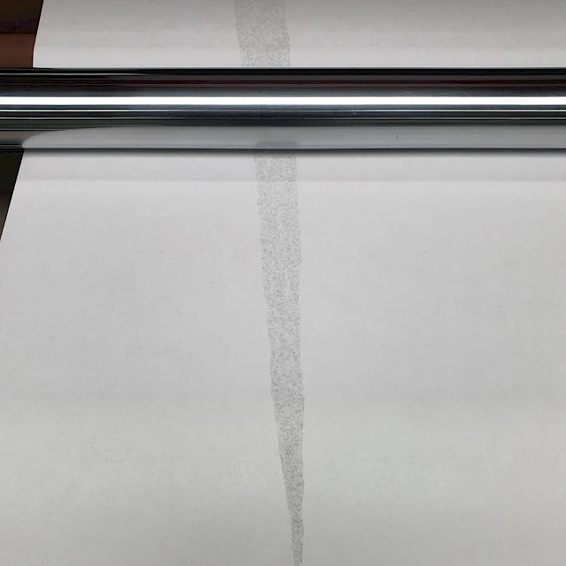 White paper web with defect streak over roller