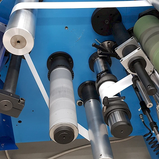 White web threaded through rollers on blue machine